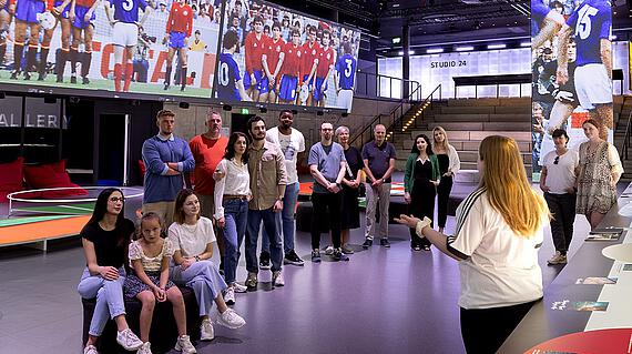 The curators of the exhibition <a href="https://www.fussballmuseum.de/inmotion"><b>„In Motion – Art & Football"</b></a>, Carina Bammesberger and Janine Horstmann, guide visitors through the immersive exhibition following a thematic introduction. After the joint viewing of the show, visitors can explore additional elements of the exhibition, including the context lounge, the studio table, and the digital gallery.<br>"In Motion – Art & Football" is a multimedia spatial installation at the German Football Museum, presented on the occasion of the 2024 European Football Championship in Germany. This exhibition showcases European art that depicts football in all its facets—both on and off the field.

The exhibition delves into the interplay between football and its artistic representation, offering new dimensions for both football fans and art enthusiasts. In 16 chapters, selected artworks trace the journey from the original essence of the game through complex gameplay scenarios to the influences of war and social upheavals. These turning points introduce new perspectives and characters, reshaping the myth of football. The exhibition illustrates how external and internal influences have transformed the sport, making its original innocence scarcely recognizable. Ultimately, it is up to the viewers to decide how football is perceived.
<br>The tour is <b>conducted in German</b>.<br><br><b>Start time:</b> Thursdays at 11 AM<br><b>Duration:</b> 120 minutes<br>
<br><b>Cost:</b> Euro per person. <br>Please note that museum admission is charged separately.